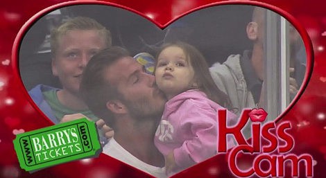 David Beckham besa a Harper Seven durante un partido de hockey