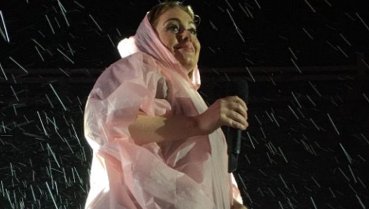Adele protegiéndose de la lluvia con un chubasquero rosa 