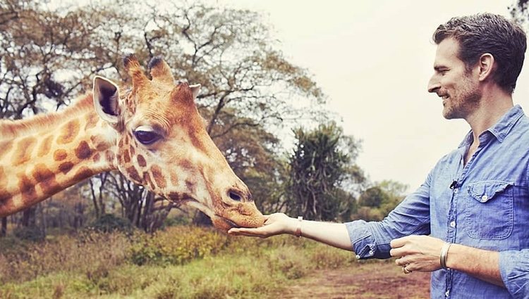 El fotógrafo británico dando de comer a una jirafa | Foto: Instagram