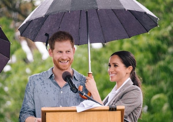 Meghan Markle sostiene el paraguas del Príncipe Harry