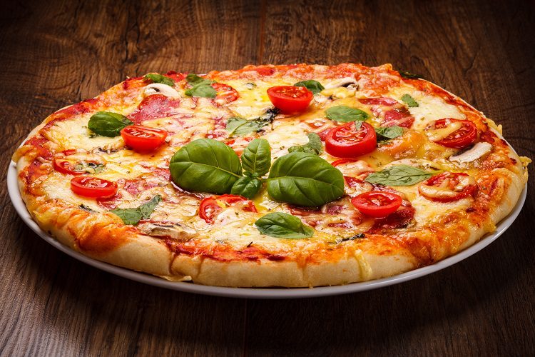 Una vez sacada la pizza del horno, añade las hojas de albahaca y un chorro de aceite de oliva virgen extra
