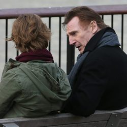 Liam Neeson y Thomas Brodie Sangster sentados en un banco en una de las secuencias de 'Love Actually 2'