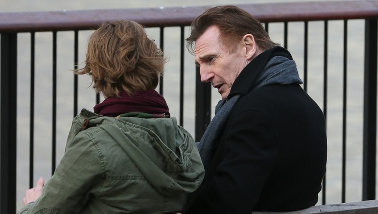 Liam Neeson y Thomas Brodie Sangster sentados en un banco en una de las secuencias de 'Love Actually 2'