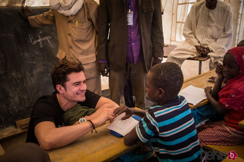 Orlando Bloom sonríe a un niño en un campamento de Unicef