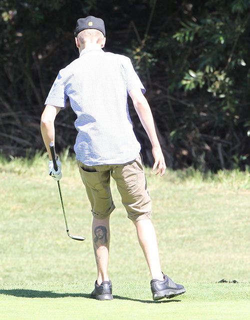 Justin Bieber jugando a golf y enseñando su tatuaje de Cristo