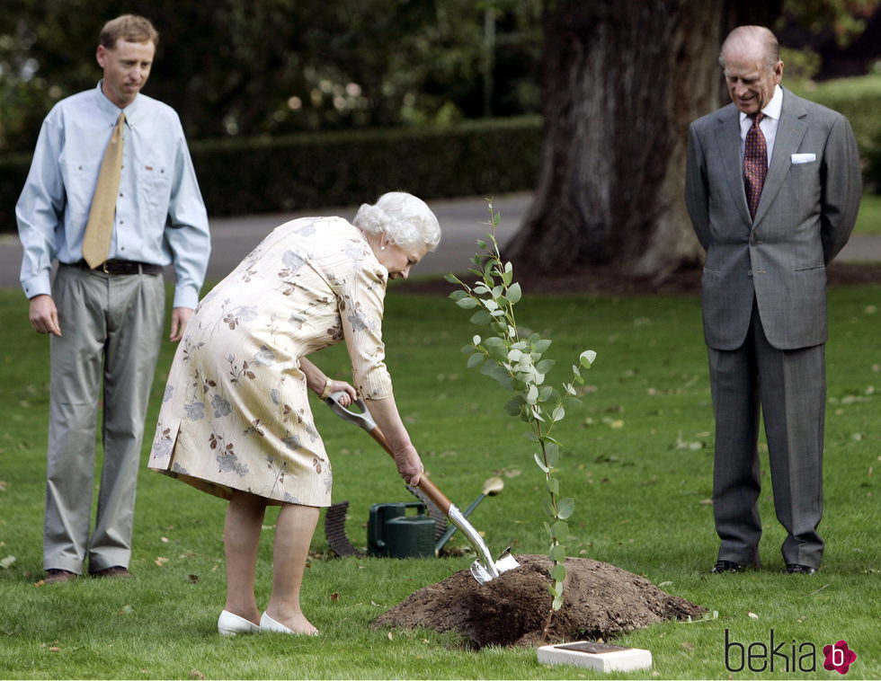 La Reina Isabel planta un árbol mientras el Duque de Edimburgo le observa