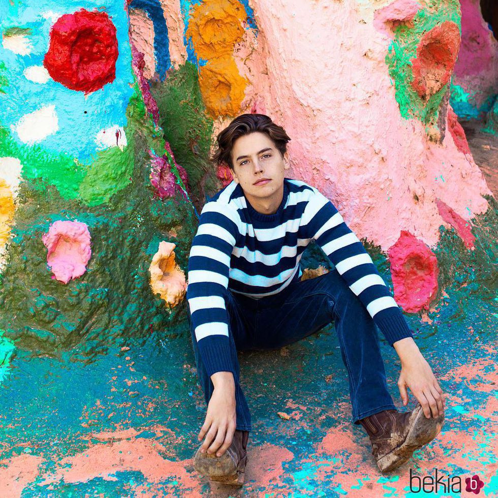 Cole Sprouse posando en una pared coloreada
