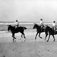 La Reina Isabel y la Princesa Margarita montando a caballo en la playa de jóvenes