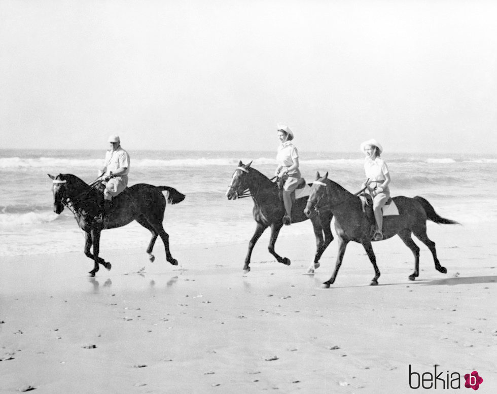 La Reina Isabel y la Princesa Margarita montando a caballo en la playa de jóvenes