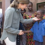 La Reina Letizia con un niño en la granja Naatangué de Senegal
