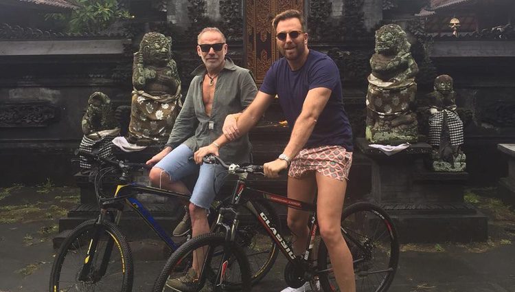Joaquín Torres y Raúl Prieto en un lugar paradisíaco montados en una bicicleta