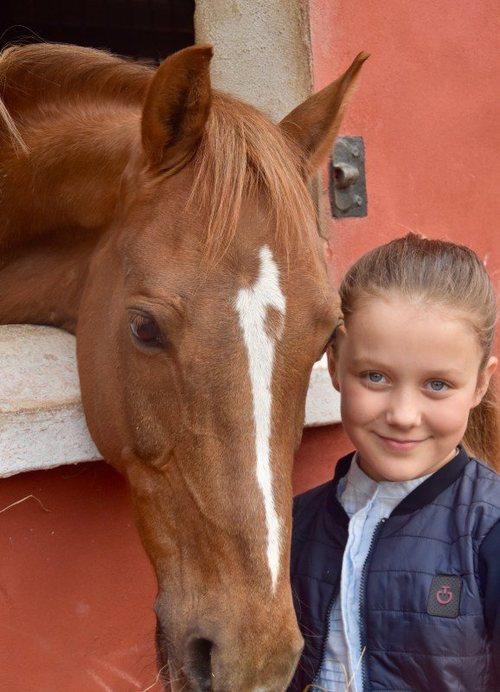 Isabel de Dinamarca sonriente junto a un caballo en su onceavo cumpleaños
