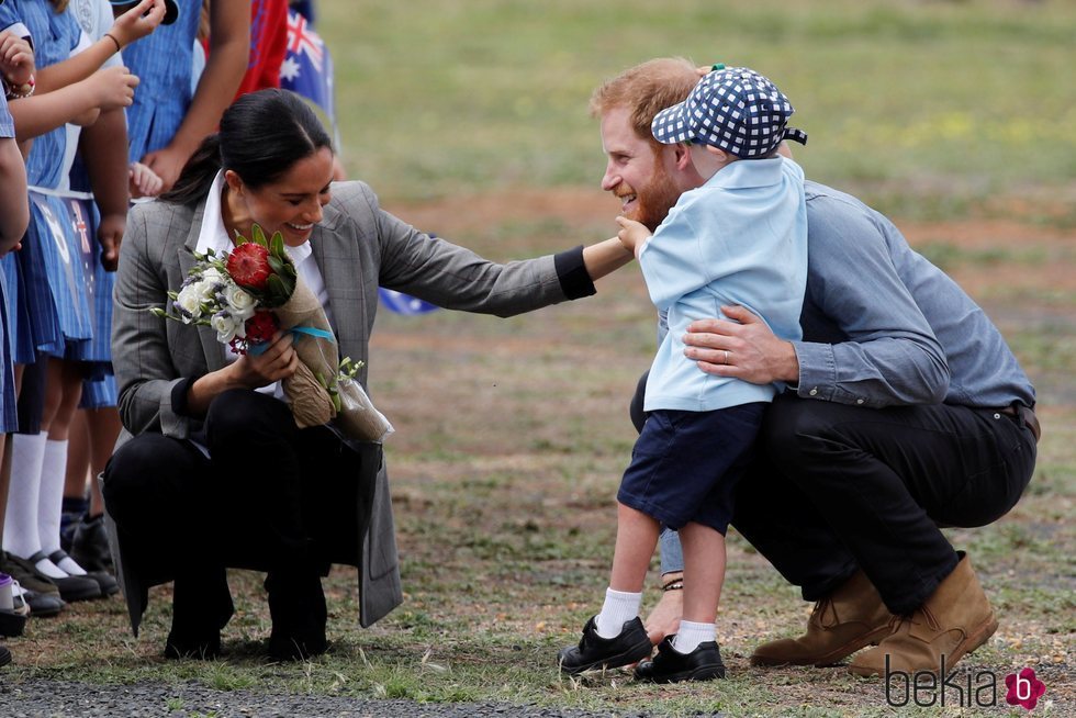 Meghan Markle ríe divertida mientras un niño toca la barba del Príncipe Harry