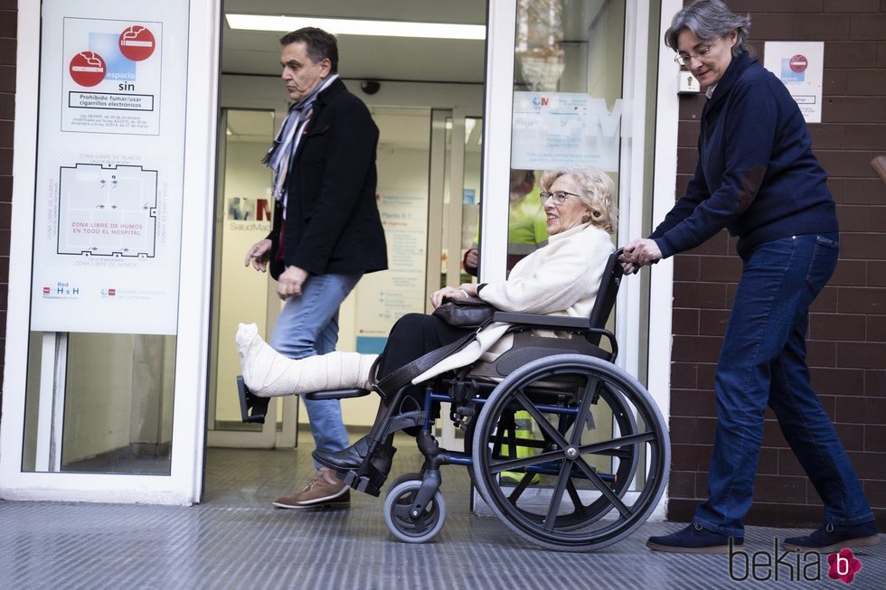 Manuela Carmena en silla de ruedas saliendo del hospital