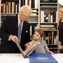 Carlos Gustavo de Suecia enseña un libro a Estela de Suecia junto a Victoria de Suecia en la Biblioteca Bernadotte