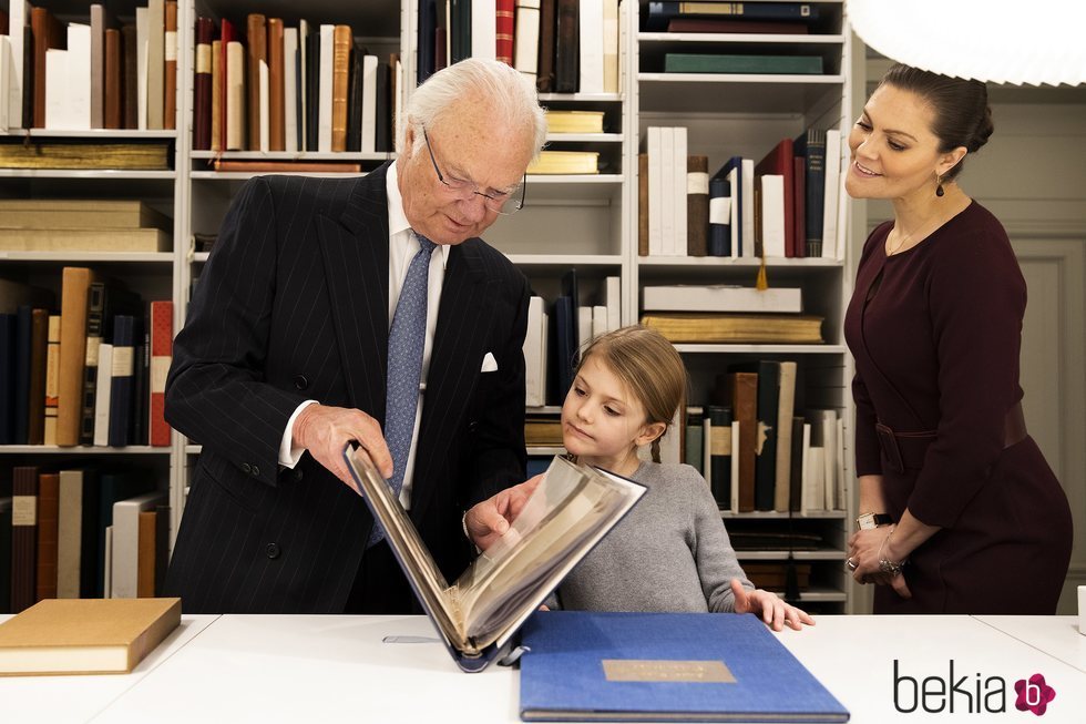 Carlos Gustavo de Suecia enseña un libro a Estela de Suecia junto a Victoria de Suecia en la Biblioteca Bernadotte