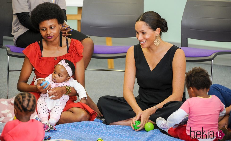 Meghan Markle con una mujer y unas niñas en su visita a Mothers 2 Mothers en Sudáfrica