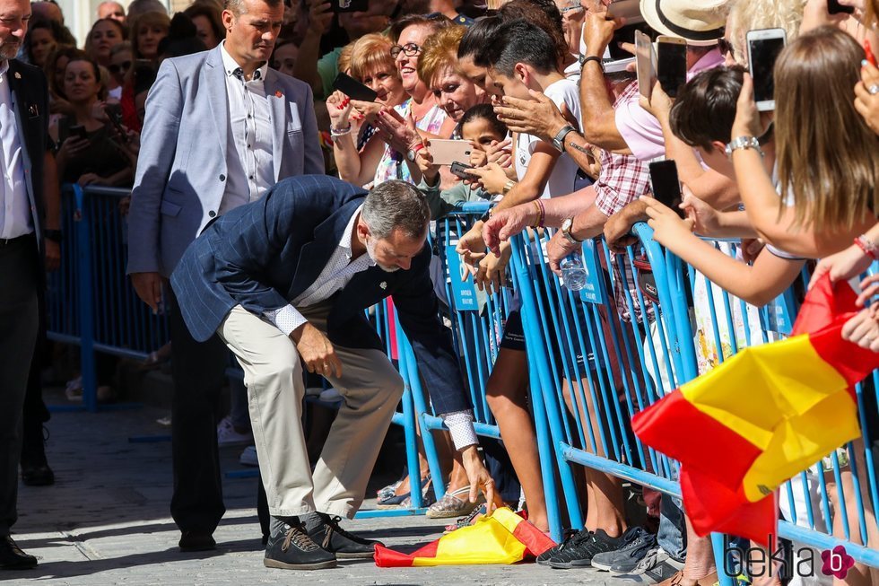 El Rey Felipe VI recogiendo una bandera de España del suelo en la visita a Orihuela