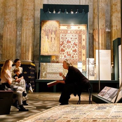 Victoria de Suecia y sus hijos Estela y Oscar de Suecia escuchan explicaciones en una exposición de alfombras