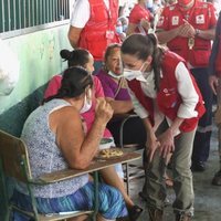 La Reina Letizia escucha el testimonio de una persona refugiada en un albergue en su viaje humanitario a Honduras