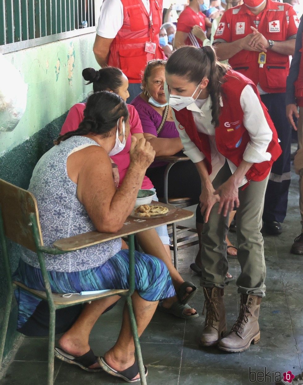 La Reina Letizia escucha el testimonio de una persona refugiada en un albergue en su viaje humanitario a Honduras