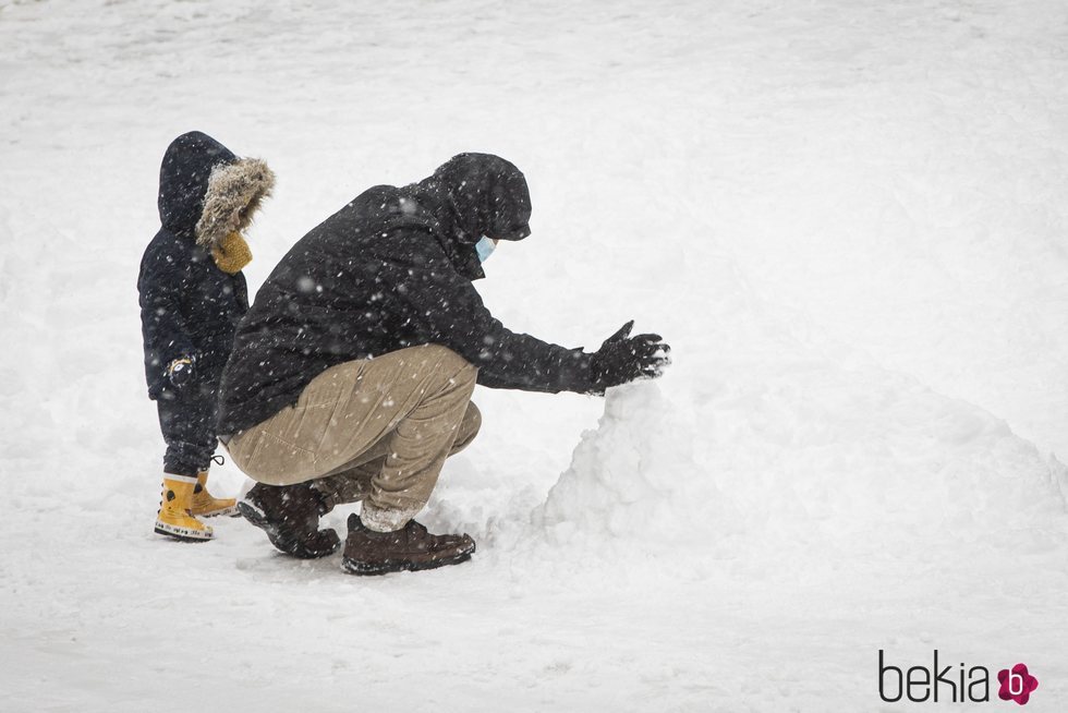 Dos ciudadanos haciendo un muñeco de nieve tras la gran nevada de Madrid de 2021 provocada por Filomena