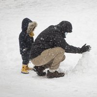 Dos ciudadanos haciendo un muñeco de nieve tras la gran nevada de Madrid de 2021 provocada por Filomena