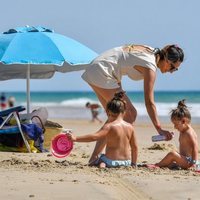Irene Rosales echa protector solar a sus hijas en la playa
