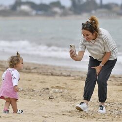 Toñi Moreno, haciendo una foto a su hija Lola en la playa