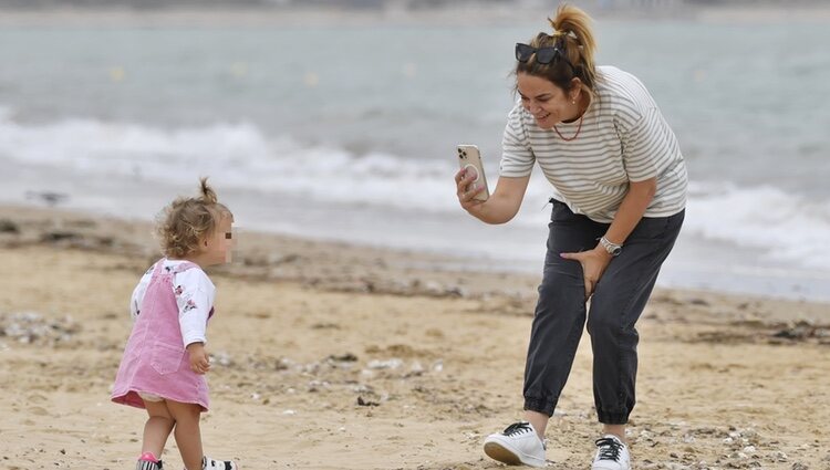 Toñi Moreno, haciendo una foto a su hija Lola en la playa