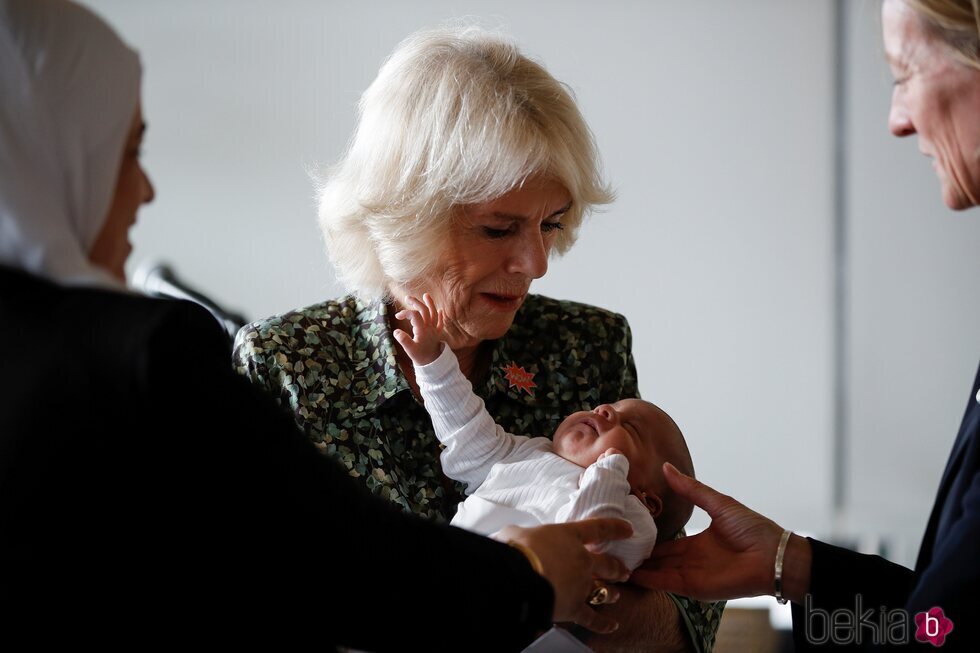 Camilla Parker sosteniendo a un bebé durante su visita oficial a Jordania