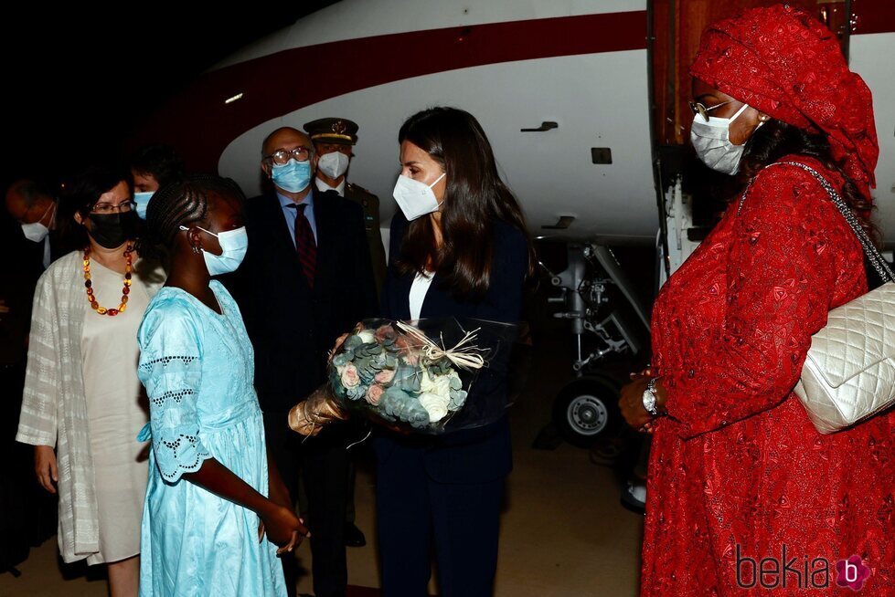 La Reina Letizia recibe un ramo de flores de manos de una niña a su llegada a Senegal