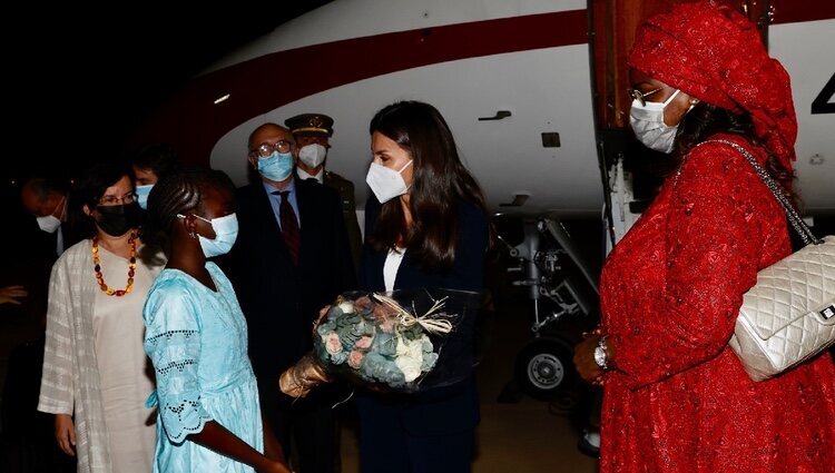 La Reina Letizia recibe un ramo de flores de manos de una niña a su llegada a Senegal