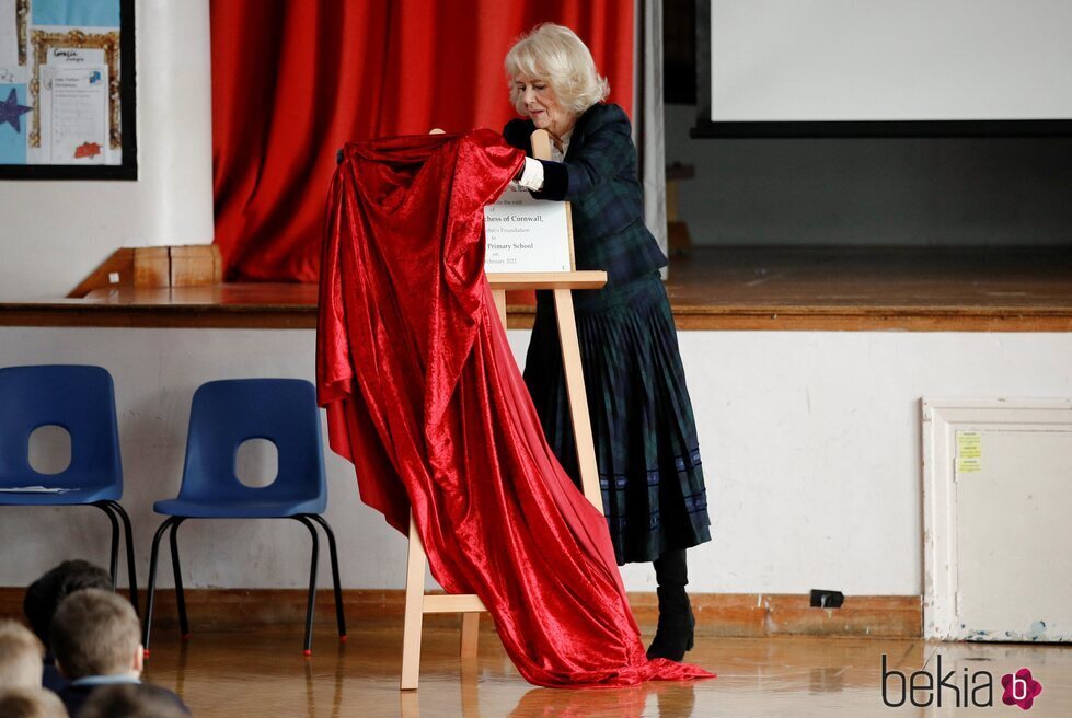 Camilla Parker tratando de retirar una tela que cubre una placa en su visita a la Escuela Roundhill de Bath