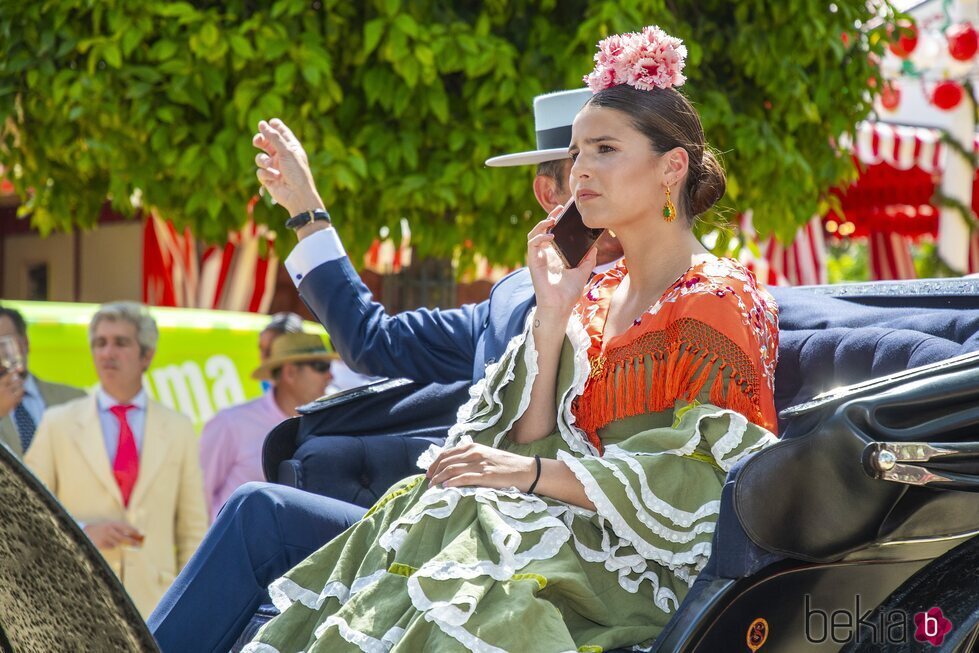 Tana Rivera hablando por el móvil en un coche de caballos en la Feria de Abril 2022