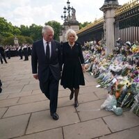 El Rey Carlos y la Reina Camilla miran las flores a las puertas del Buckingham Palace