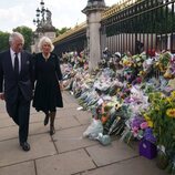 El Rey Carlos y la Reina Camilla miran las flores a las puertas del Buckingham Palace