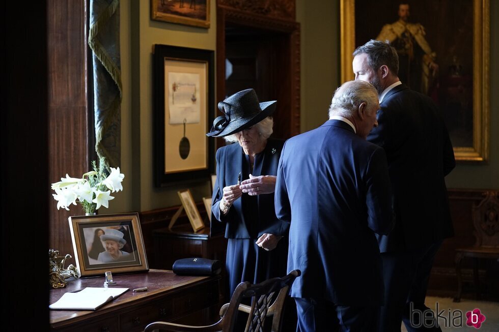 El Rey Carlos III con la Reina Camilla teniendo problemas con la pluma estilográfica