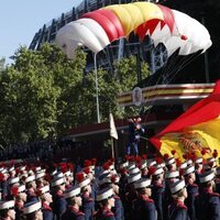El paracaidista Óscar García aterriza ante la tribuna real con la bandera de España en el desfile militar por la Fiesta Nacional 2022