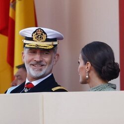 El Rey Felipe VI sonríe a la Reina Letizia en el desfile militar por la Fiesta Nacional 2022