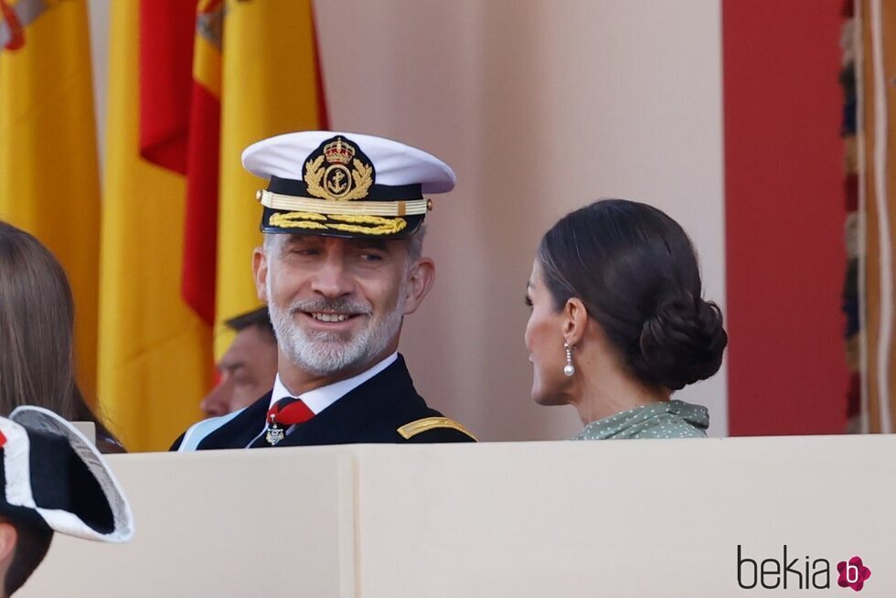 El Rey Felipe VI sonríe a la Reina Letizia en el desfile militar por la Fiesta Nacional 2022