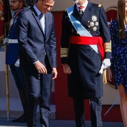 Pedro Sánchez y Felipe VI bromeando en el desfile militar por la Fiesta Nacional 2022