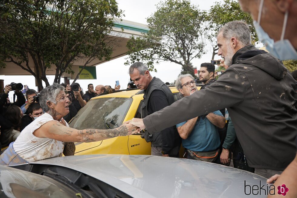 El Rey Felipe VI da la mano a una mujer en Paiporta en su visita a las zonas afectadas por la DANA en Valencia