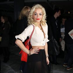 Rita Ora con camisa blanca, maxi falda en negro y complementos en rojo