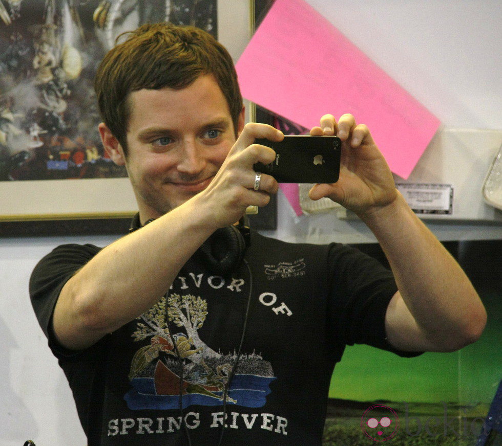 Elijah Wood sonríe con su iPhone