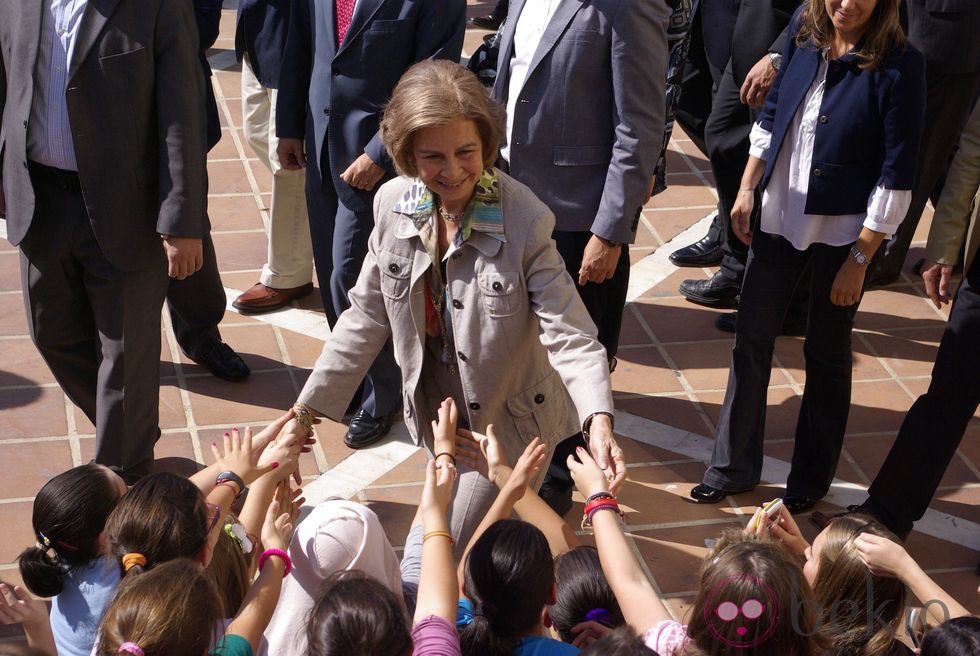 La Reina Sofía saluda a unos niños durante su visita a los afectados por las inundaciones en Málaga