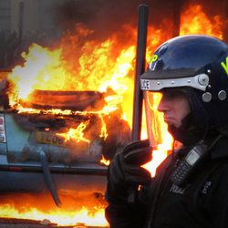 Un policía junto a un coche en llamas en los disturbios de Londres