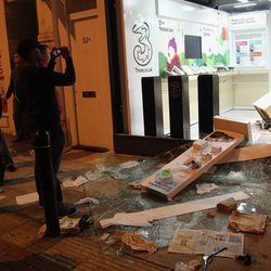 Varias personas fotografían una tienda saqueada en los disturbios de Londres