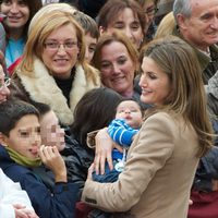 La Princesa de Asturias con un bebé en brazos durante su visita a Caspe