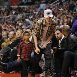 Justin Bieber con un niño de la mano en la NBA
